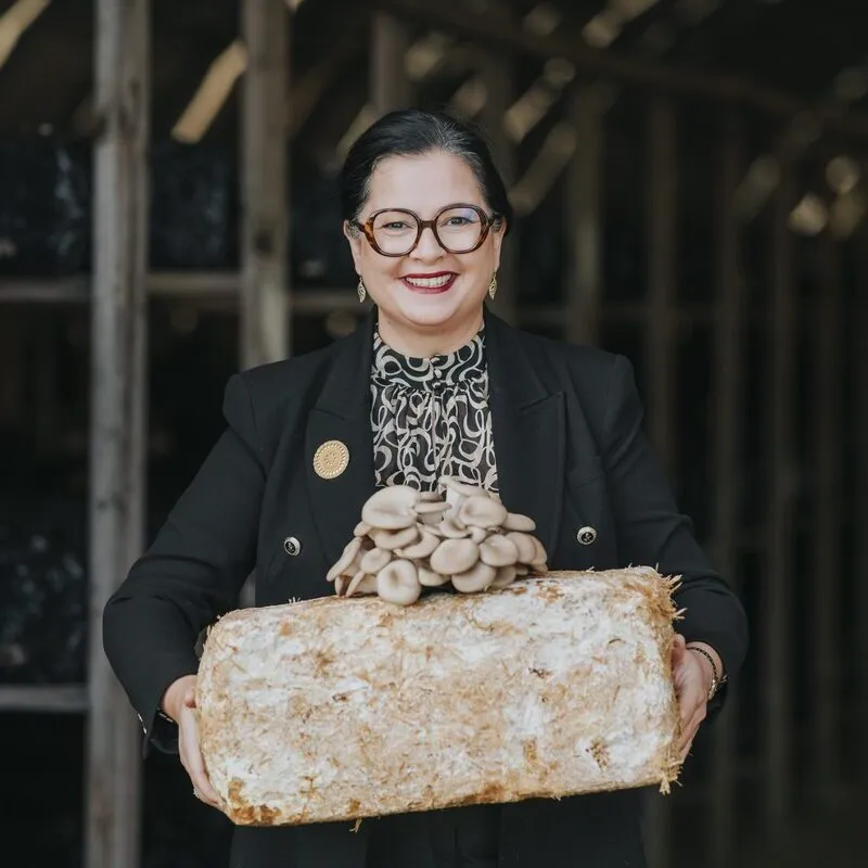 Une femme présente des champignons exotiques ayant poussé sur un susbstrat - Illustration Dans le monde du champignon exotique