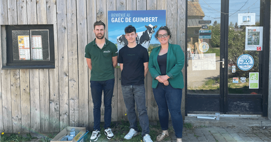 trois personnes devant l'affiche du gaec de guimbert