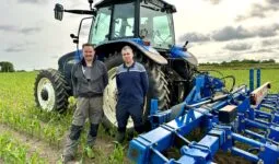 Deux personnes devant un tracteur dans un champ de maïs.
