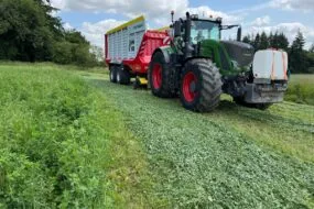 Un tracteur équipée d'un remorque autochargeuse dans une parcelle de luzerne