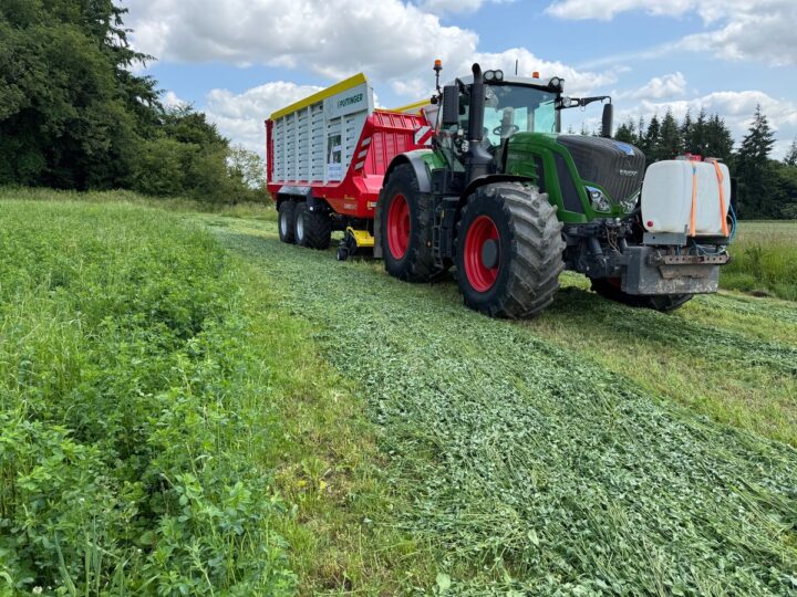 Un tracteur équipée d'un remorque autochargeuse dans une parcelle de luzerne