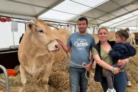 Une vache de race Blonde d'Aquitaine avec un couple d'éleveurs et une enfant