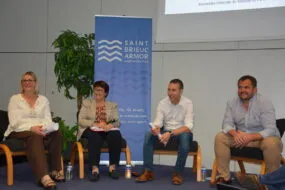 Quatre personnes assises à une tribune pour une table ronde
