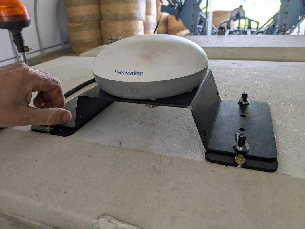 L’antenne GNSS est montée sur une platine venant se fixer, à l’aide de quatre vis papillons, sur deux supports collés au toit de la cabine.