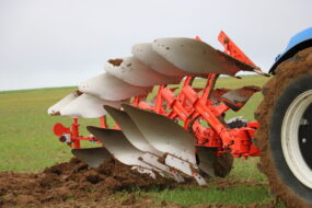 Gros plan dans un champ sur une charrue attelée à l'arrière d'un tracteur