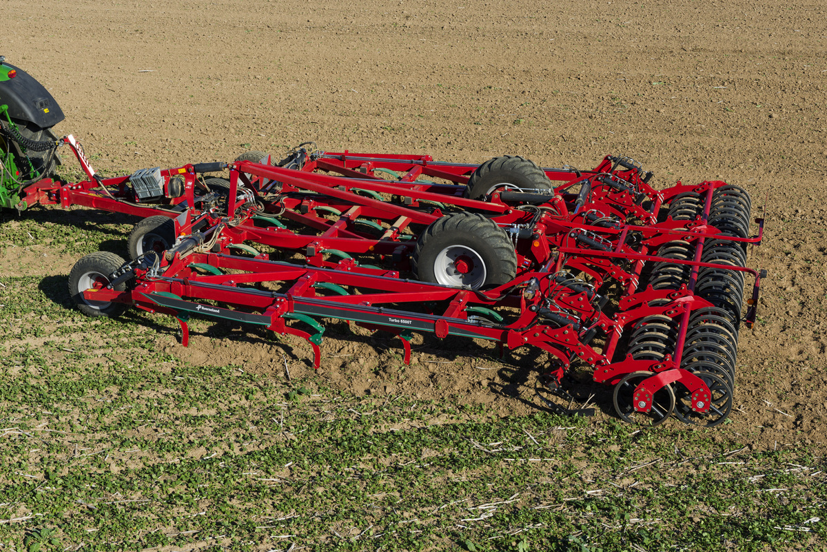 Un déchaumeur attelé à un tracteur au travail dans un champ