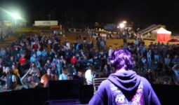 Un DJ de dos sur une scène avec une foule devant en train de danser dans une fête de l'agriculture