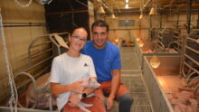 Un homme et une jeune fille souriants dans un élevage de porc
