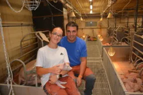 Un homme et une jeune fille souriants dans un élevage de porc