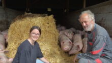 Une femme et un homme avec des cochons sur de la paille