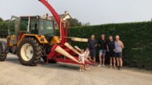 Des personnes posent avec un modèle ancien d'ensileuse