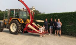 Des personnes posent avec un modèle ancien d'ensileuse