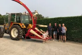 Des personnes posent avec un modèle ancien d'ensileuse