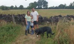 Un couple et un enfant au milieu d'un troupeau de chèvre dans un champ