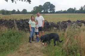 Un couple et un enfant au milieu d'un troupeau de chèvre dans un champ