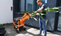 un homme passe les brins de maïs dans un hachoir