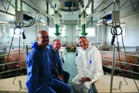 Un éleveur et des techniciensdans un bâtiment d'élevage de porc