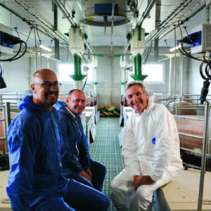 Un éleveur et des techniciensdans un bâtiment d'élevage de porc