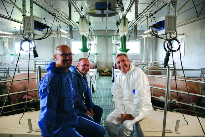 Un éleveur et des techniciensdans un bâtiment d'élevage de porc