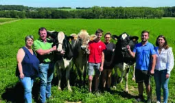 Une famille d'éleveurs présente deux vaches Holstein et une vache Brune.