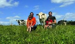 Un couple d'élevurs et leurs deux fils dans une prairie avec des vaches de race Holstein.