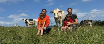 Un couple et 2 enfants assis dans un champ avec des vaches autour