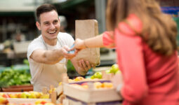 Un commerçant sur un marché de fruits et légumes qui prend la monnaie d'une cliente