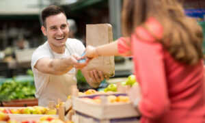 Un commerçant sur un marché de fruits et légumes qui prend la monnaie d'une cliente