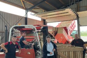 Trois hommes et une femme sous un hangar de réception et de tri de pommes de terre.s