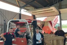 Trois hommes et une femme sous un hangar de réception et de tri de pommes de terre.s