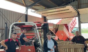 Trois hommes et une femme sous un hangar de réception et de tri de pommes de terre.s