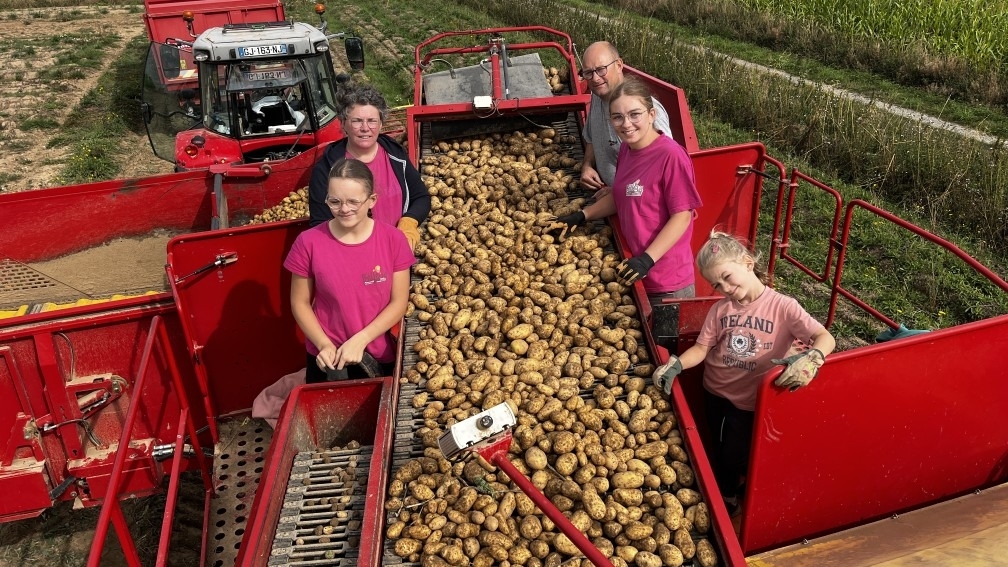 Un couple de producteurs de pommes de terre et leurs trois filles autour d'une machine à récolter.