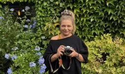 Une femme tenant un appareil photographique dans les mains.