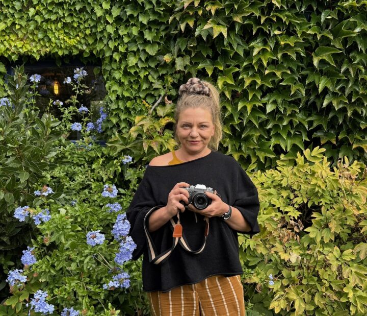 Une femme tenant un appareil photographique dans les mains.