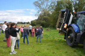 Groupe de personnes dans un champ devant un tracteur
