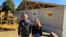 Un homme et une femme devant un chantier de construction d'un bâtiment d'élevage de porcs