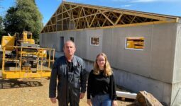 Un homme et une femme devant un chantier de construction d'un bâtiment d'élevage de porcs