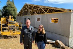 Un homme et une femme devant un chantier de construction d'un bâtiment d'élevage de porcs