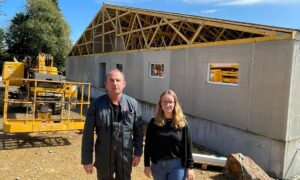 Un homme et une femme devant un chantier de construction d'un bâtiment d'élevage de porcs