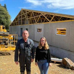 Un homme et une femme devant un chantier de construction d'un bâtiment d'élevage de porcs