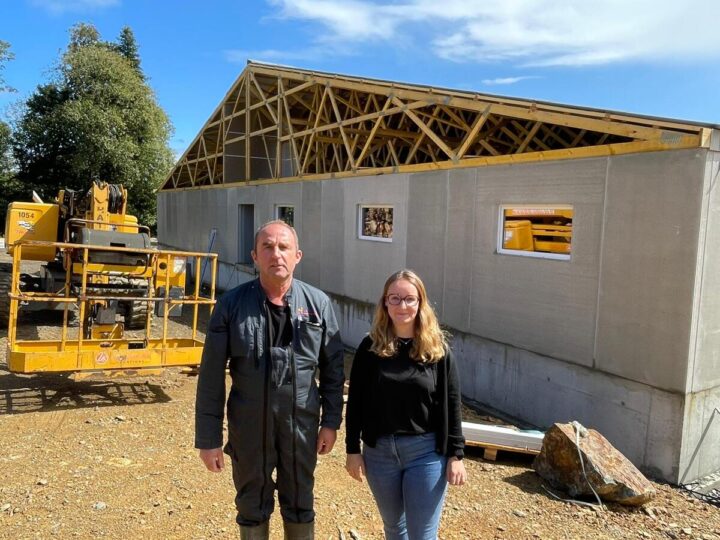 Un homme et une femme devant un chantier de construction d'un bâtiment d'élevage de porcs