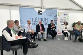 Un groupe de personnes assises sous un chapiteau lors d'un débat