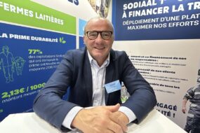 Un homme souriant sur un salon avec les mains croisées sur une table