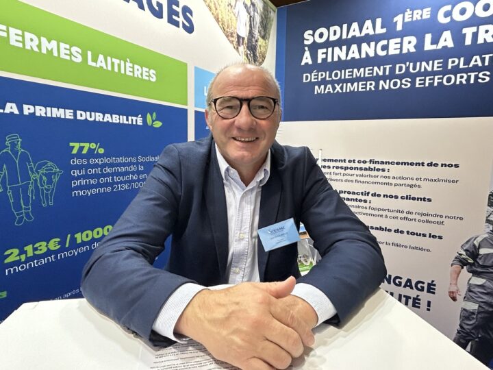 Un homme souriant sur un salon avec les mains croisées sur une table