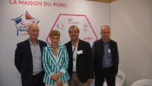 Quatre personnes posent sur le stand de la maison du porc sur un salon