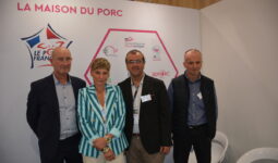 Quatre personnes posent sur le stand de la maison du porc sur un salon
