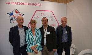 Quatre personnes posent sur le stand de la maison du porc sur un salon