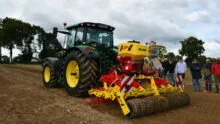 Un tracteur avec son semoir et des gens qui regardent