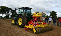 Un tracteur avec son semoir et des gens qui regardent