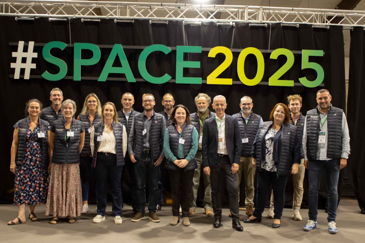Un groupe de personnes pose devant une enseigne du Space 2025 - Illustration Paysan Breton fête ses 80 ans au Space